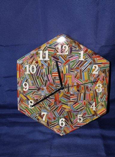 Bunte hexagonale Uhr mit bunten Streifen und schwarzen Zeigern.