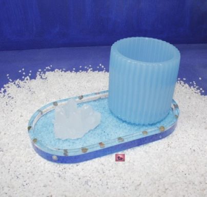 Blauer Becher auf einer ovalen Unterlage mit kristallinem Couchtischdesign.