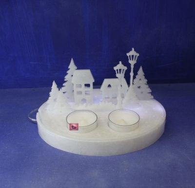 Dekorative Winterlandschaft mit Häusern, Bäumen und zwei Teelichthaltern.