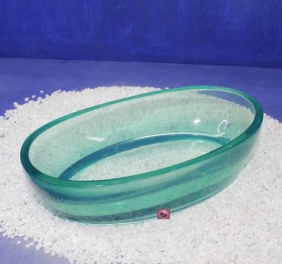 Grüner, ovaler Glasbehälter auf weißem Kieshintergrund.