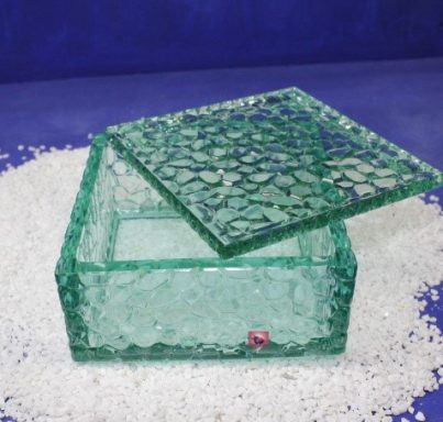 Grüne, dekorative Box mit aufliegendem, strukturiertem Deckel auf hellem Untergrund.