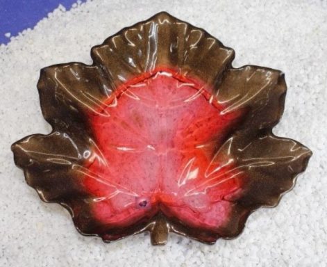 Braune Blattschale mit roter Innenseite, umgeben von weißem Kies.
