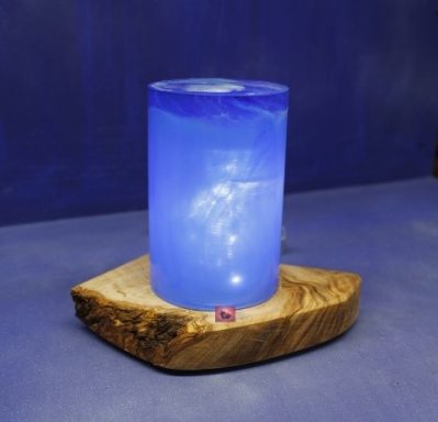 Blauer, leuchtender zylindrischer Leuchter auf einem Holzuntergrund.