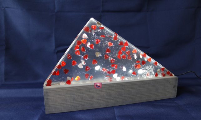 Dreieckige Struktur mit roten/ silber, reflektierenden Glitzerherzen in klarem Epoxidharz.