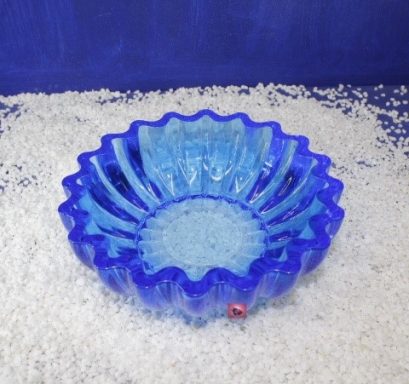 Blauer, gewellter Glasschüssel auf einer Fläche mit weißem Streu.