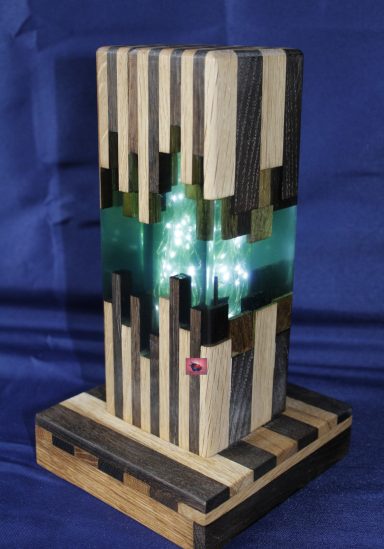 Holzlampe mit leuchtendem, grünem Mittelteil und geometrischem Design.