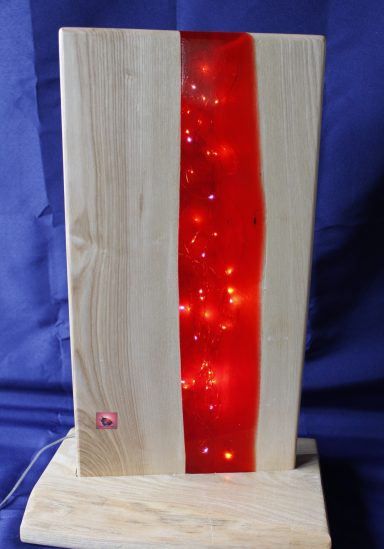 Holzlampe mit rotem Harzstreifen und eingebetteten Lichtern.